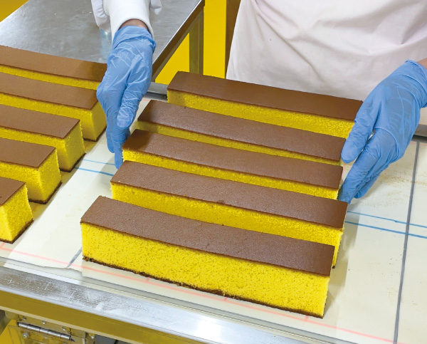 カステラを作業員が一本一本ていねいに心を込めて並べています。